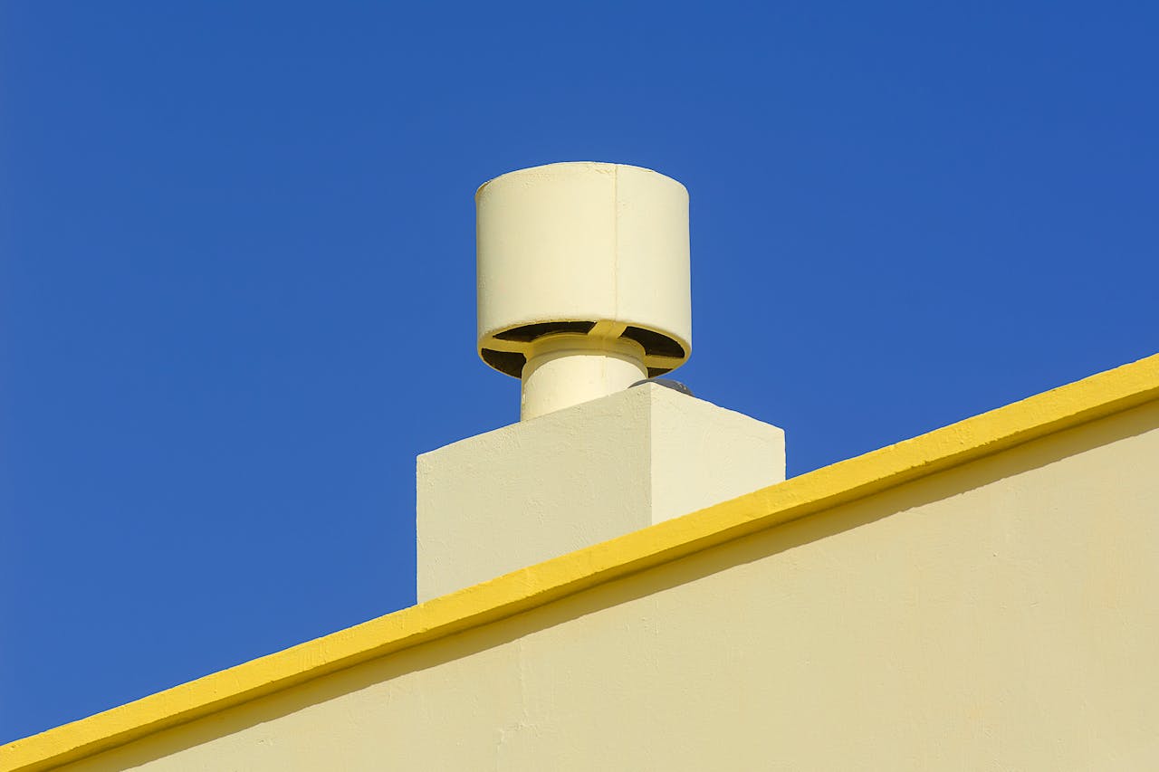 why-choose-us Yellow industrial chimney against a vibrant blue sky, representing modern architecture.