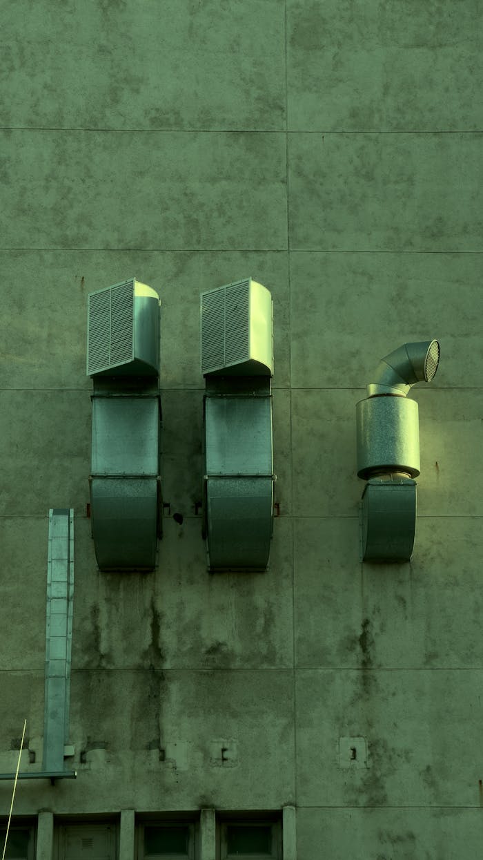 Close-up of industrial ventilation ducts on a city building wall.